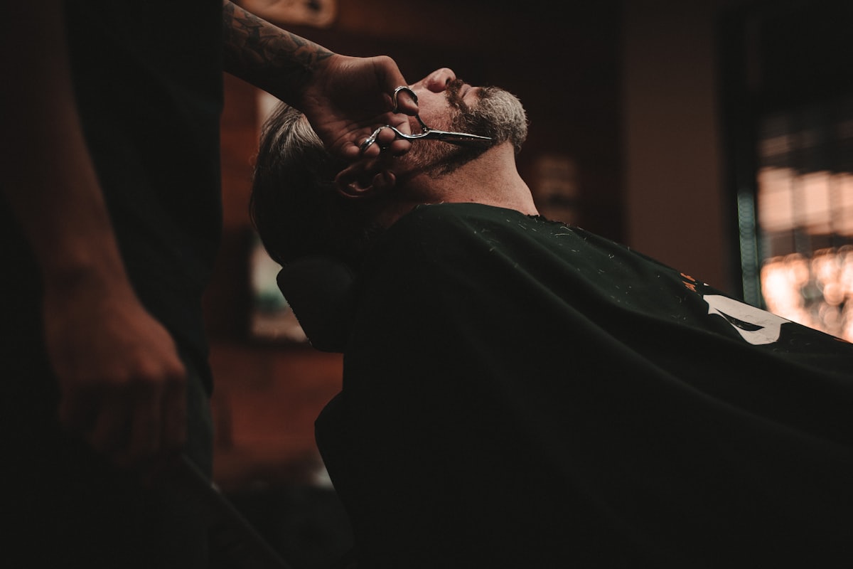 Barber trimming a client's beard in a traditional barbershop