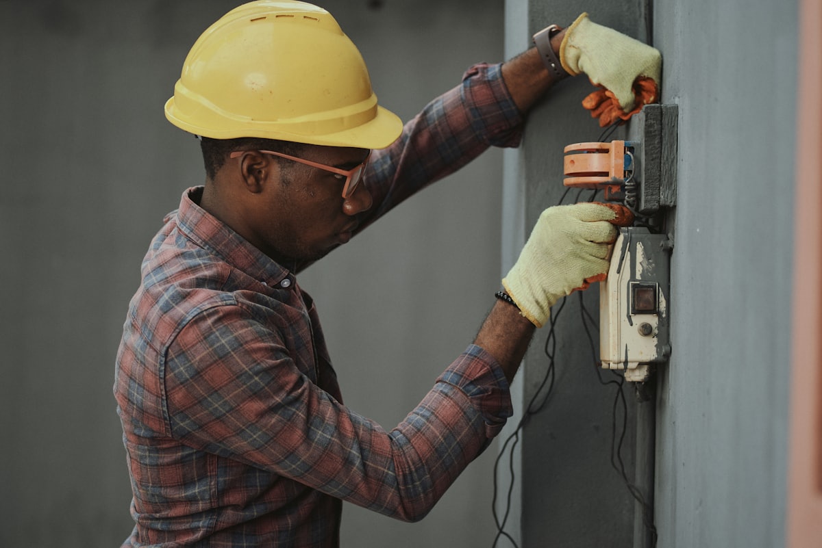 Electrician in a hard hat wiring an outdoor service panel